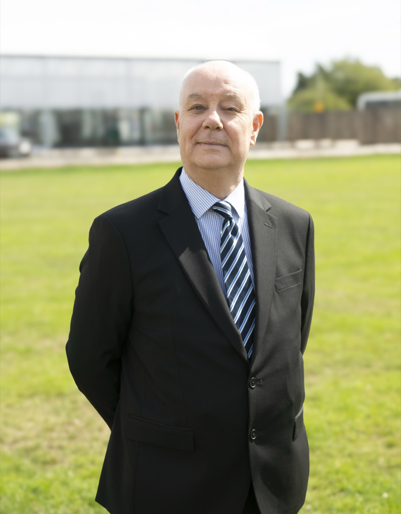 Paul Dryden standing outdoors in a dark suit and striped tie